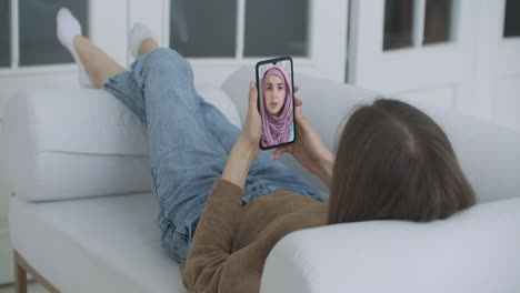 Female-using-medical-app-on-smartphone-consulting-with-Arab-Muslim-woman-in-hijab-doctor-via-video-conference.-Female-using-online-chat-to-talk-with-family-therapist-and-pandemic-of-coronavirus.